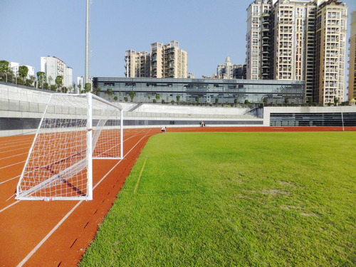 实拍深圳宝安体育馆足球场景观，有工人在维护有市民在跑步