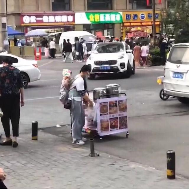 一个女人背着孩子卖菜,女人背着一岁孩子卖菜